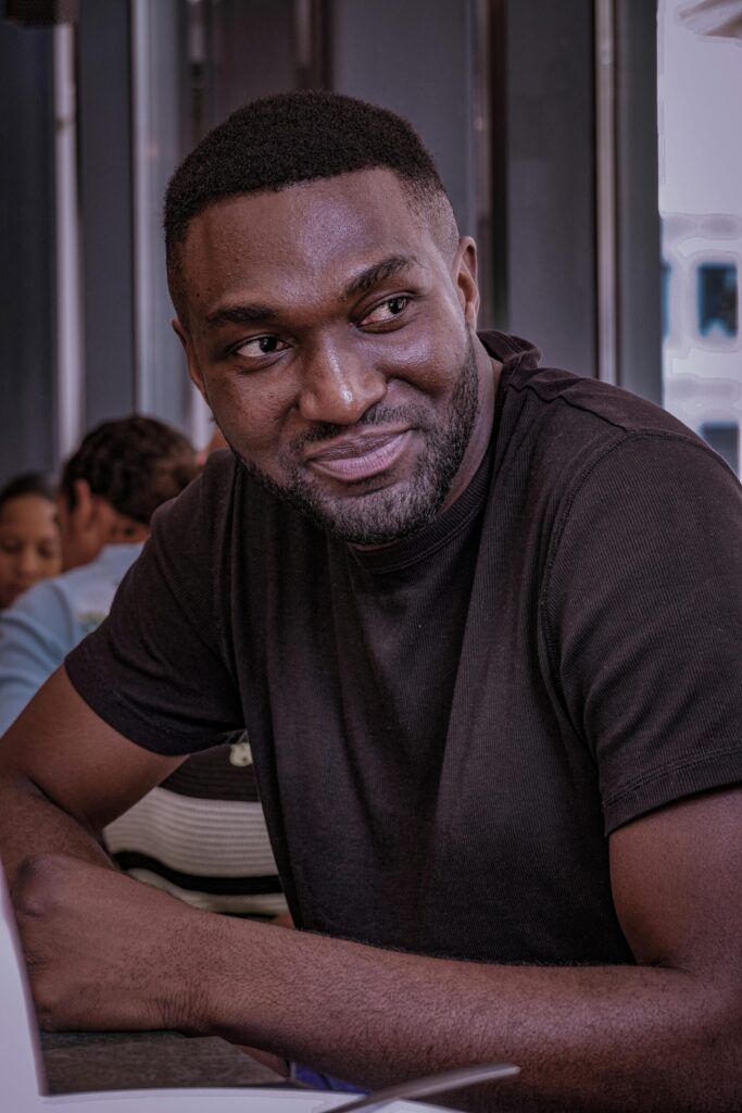 pexels photo 33812350 33812350 Confident man smiling while seated at an indoor café setting.